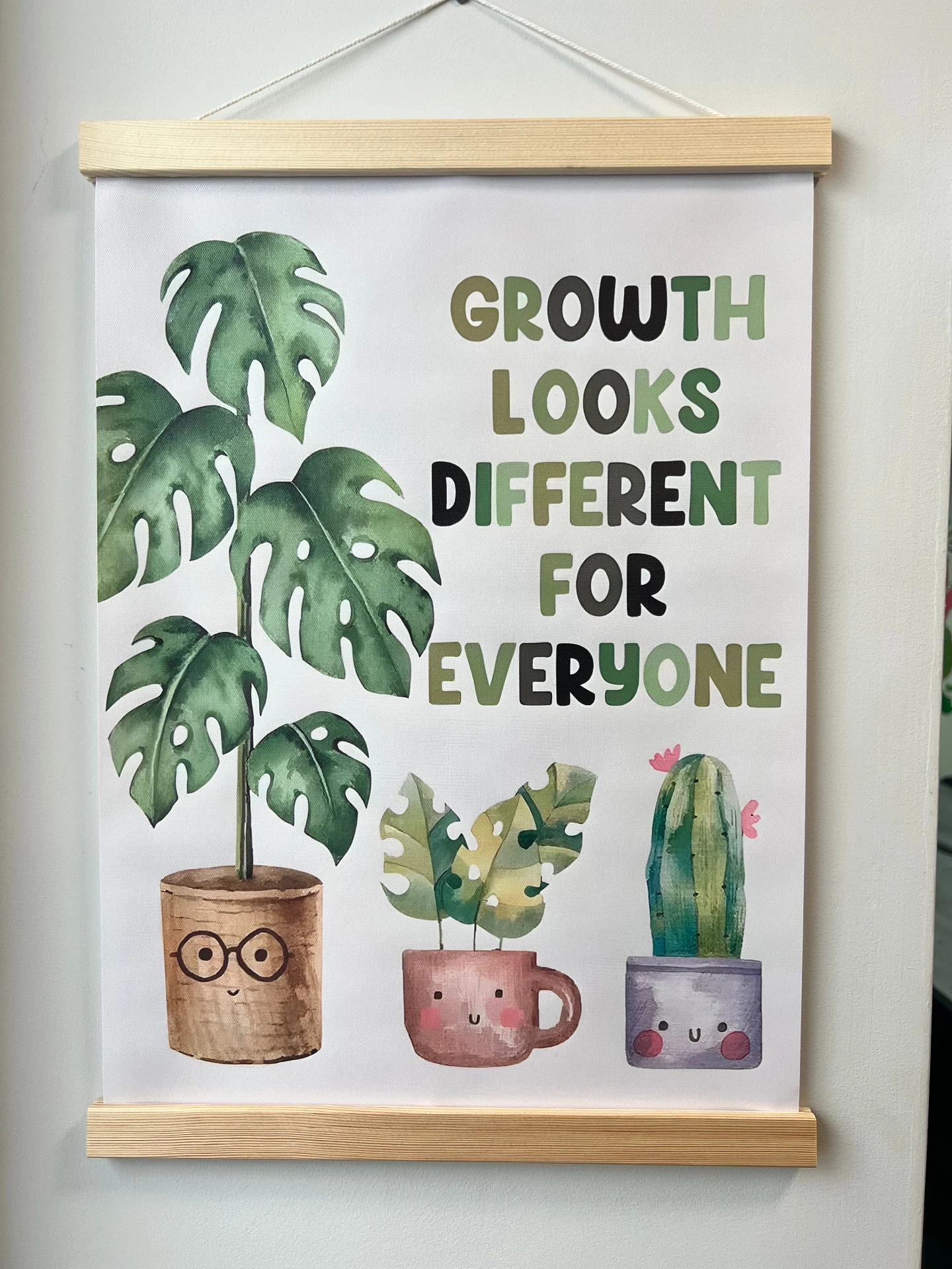 A wall poster showing potted plants with the message 'Growth looks different for everyone'