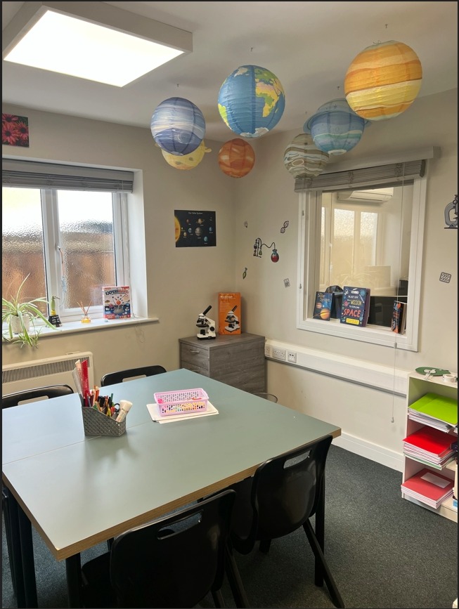 Classroom with grouped tables and planet mobiles hanging from the ceiling